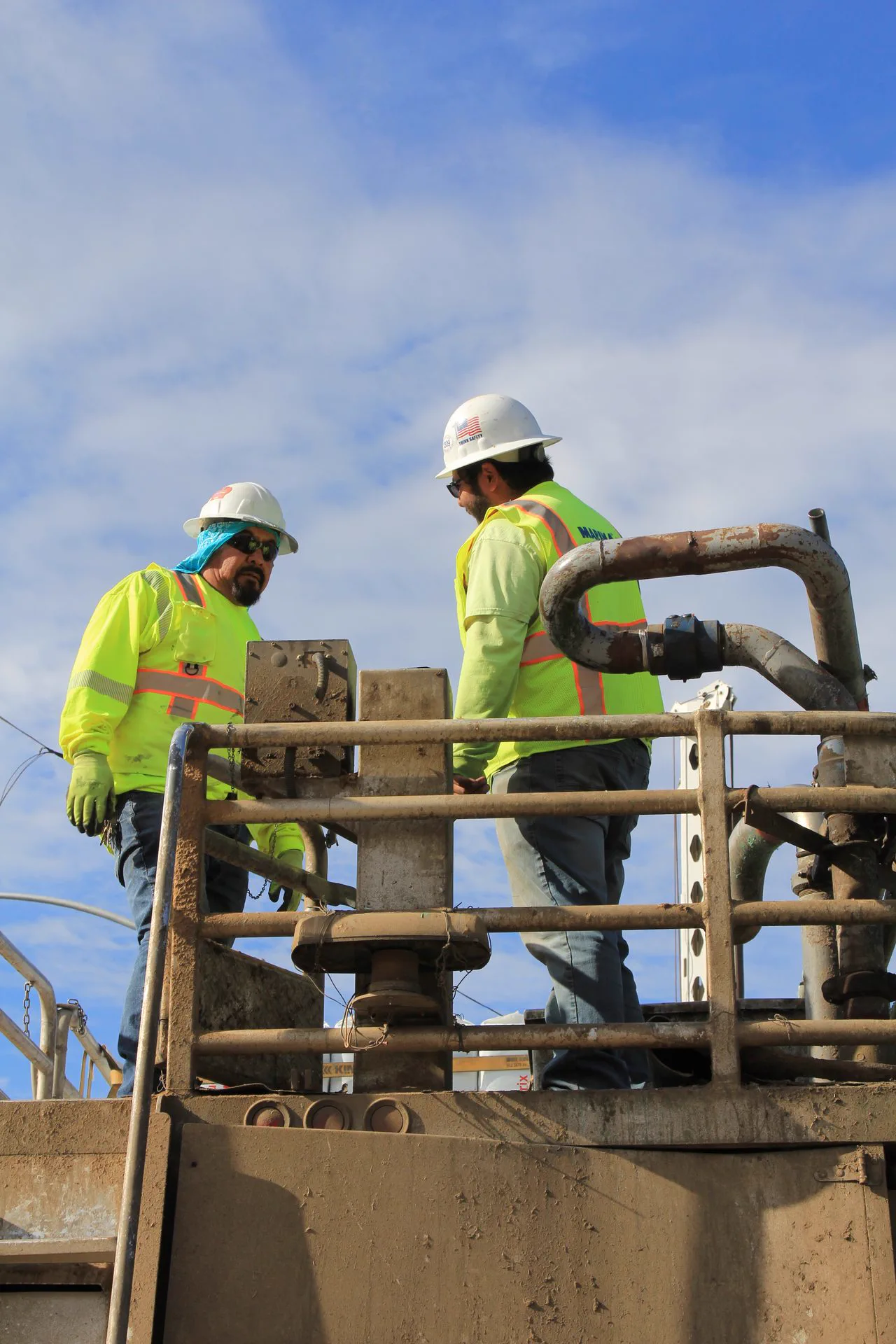 Marina crew in hard hats, safety glasses and gloves working on a pump assembly